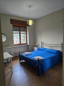 a bedroom with a blue bed and a desk and a window at B&B Camposauro in Vitulano