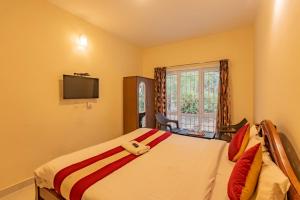 a bedroom with a bed and a tv on the wall at Riyan Valley Resort in Ooty