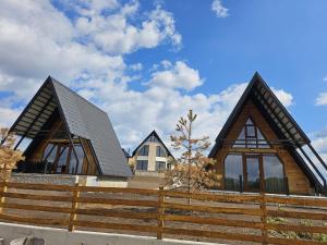 a house with two pointed roofs and a wooden fence at Brvnare na Oku Zlatibor in Ocka Gora