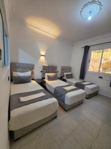 ein Schlafzimmer mit drei Betten und einem Fenster in der Unterkunft Ammour Apartment in Chefchaouen