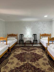 a room with two beds and a table and chairs at Parivash Guest House in Bukhara