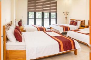 a hotel room with four beds and a window at Việt Hà Motel in Bảo Lạc