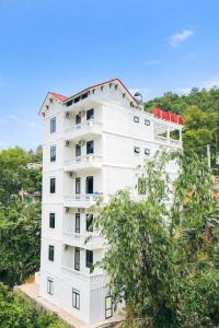 a white building with trees in front of it at Việt Hà Motel in Bảo Lạc