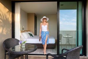 a woman in a hat standing in a hotel room at Kata Beach Pool View Condo - 400m from the Beach in Kata Beach
