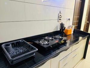 a kitchen with a black counter top with a stove at Palm Suite With Sky Terrace Penthouse 11th Floor in Rajkot