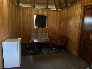 a room with a refrigerator and a table and a chair at Emms Cubango Ecological Camp in Divundu