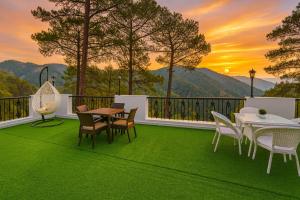 a patio with a table and chairs on a green floor at Hotel Ambience Hill Nainital - near Bhowali in Nainital
