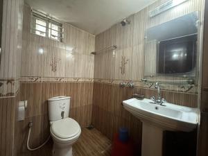 ein Badezimmer mit Toilette, Waschbecken und Fernseher in der Unterkunft Muscat Holiday Resort in Cox's Bazar