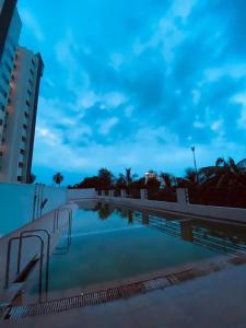 a swimming pool at night with a building at Palm Suite With Sky Terrace Penthouse 11th Floor in Rajkot