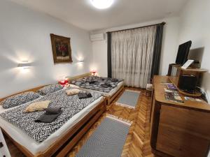 a bedroom with two beds and a desk and a window at Toldi 5 Apartman in Pécs