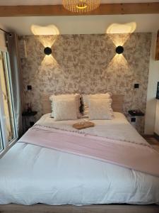 a bedroom with a large white bed with two pillows at La cabane au bout du Thérain in Herchies