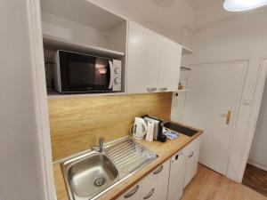 a small kitchen with a sink and a microwave at Toldi 5 Apartman in Pécs