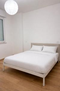 a white bed in a white room with a lamp at Biancamilla's Home in Giulianova