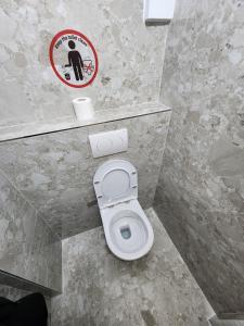 a bathroom with a toilet with a sign on the wall at The HANGOUT Hostel in Sarandë +28 photos