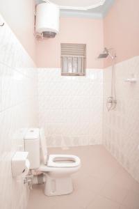a white bathroom with a toilet and a window at SILVER OAKS HOTEL Boma in Fort Portal +106 photos