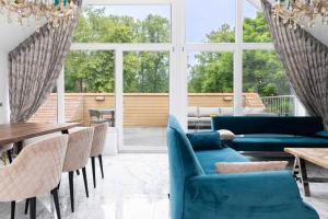 a living room with blue couches and tables and windows at Happy Day Apartment, By Cohost in Palanga