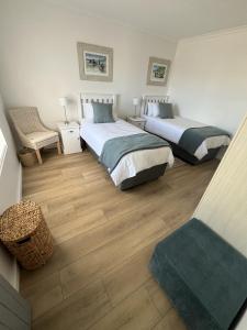 a bedroom with two beds and a chair at Codrock Cottage in Langebaan