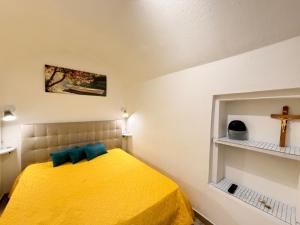 a bedroom with a yellow bed with a cross on the wall at Perla Del Borgo in Gallipoli +16 photos
