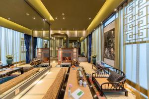 a living room with a fireplace and benches and windows at Wumo Qinglu Snow Mountain Museum Hotel in Baisha
