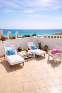 a patio with white chairs and a view of the ocean at Casa Carlotta - 100m from the Beach, Maio in Vila do Porto