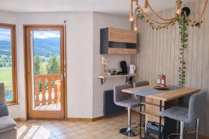 a kitchen with a table and chairs and a balcony at Haut Doubs Belvédère in Les Hôpitaux-Neufs