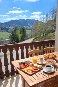 a wooden table with breakfast food on a balcony at Haut Doubs Belvédère in Les Hôpitaux-Neufs