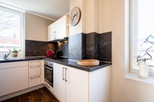a kitchen with white cabinets and a clock on the wall at Rodehuus Wohnung 4 in Borkum