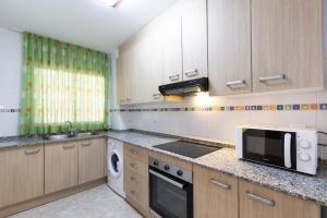 a kitchen with a microwave and a stove top oven at PINEDA NOU Apartments in La Pineda