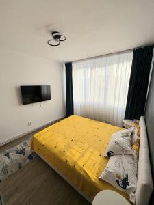 a bedroom with a bed with a yellow comforter at NiC Apartment in Râmnicu Vâlcea