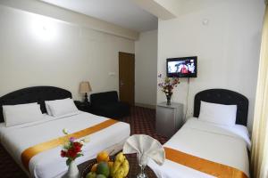 a hotel room with two beds and a table with fruit at Holiday Xpress in Dhaka