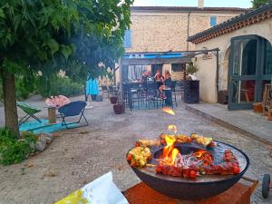 a fire pit in a yard with a group of people at Hôtel Restaurant L'Orée du Vercors in Montmaur-en-Diois