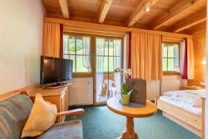 ein Wohnzimmer mit Sofa, Fernseher und Tisch in der Unterkunft Hotel Thaneller Stadl Bräu in Berwang