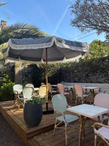 a patio with tables and chairs and an umbrella at Le Petit Café L'arriere Cour in Cancale
