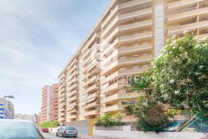 a tall building with cars parked in front of it at Señorio de Oropesa-CM in Oropesa del Mar