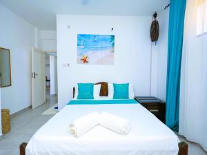 a bedroom with a large white bed with blue accents at Chui de eagle in Mombasa +62 photos