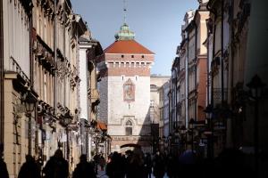 a group of people walking down a street with a clock tower at Wyndham Grand Krakow Old Town in Krakow