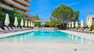 a swimming pool with chairs and umbrellas at Grand Hotel Pomorie - Medical spa in Pomorie