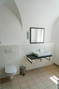 a bathroom with a sink and a toilet and a mirror at KOKORO am Kirchplatz in Sankt Veit am Vogau +45 photos
