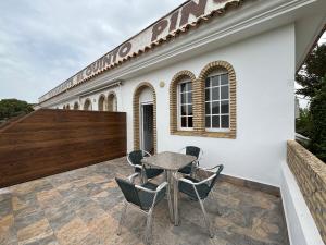 a patio with a table and chairs in front of a building at Hostal Quinto Pino in Chipiona