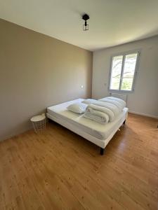 a bedroom with a bed with white sheets and a window at Maison les Boites in La Chapelle-Rousselin