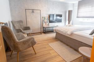 a bedroom with a bed and two chairs and a television at Ovideli Apartment in Ocna-Mureşului
