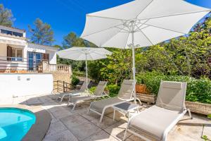 a patio with chairs and an umbrella and a pool at Bon Jardi in Esporlas