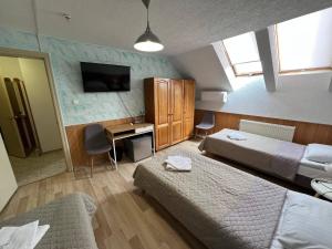 a bedroom with two beds and a desk and a television at Guest House Uzhgorod in Uzhhorod