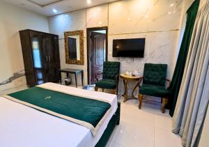 a bedroom with a bed and two chairs and a table at Golden One Hotel in Lahore