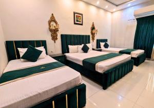 a room with three beds with green and white at Golden One Hotel in Lahore