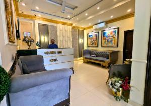 a man standing at a hair salon with two chairs at Golden One Hotel in Lahore