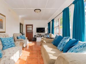 a living room with two couches and blue curtains at Haweweg 5 in Struisbaai