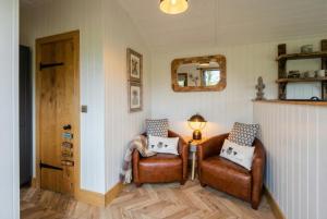 a living room with two leather chairs and a lamp at Secluded Countryside Shepherd's Hut on Working Farm near Audley in Audley
