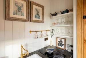 a kitchen with a sink and a shelf with cups at Secluded Countryside Shepherd's Hut on Working Farm near Audley in Audley
