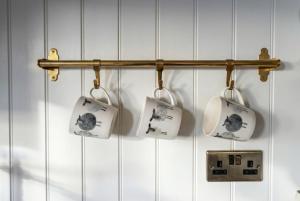 a towel rack with four cups hanging on a wall at Secluded Countryside Shepherd's Hut on Working Farm near Audley in Audley +17 photos
